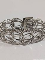 Close-up side view of silver chain link bracelet showing detail of links lengthwise.