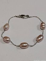 Silver freshwater pearl bracelet with five pearls on delicate silver chain, displaying clasp and pearls clearly.