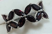 Close-up front view of sterling silver ring featuring numerous marquise garnet stones set in prongs forming a delicate linked design.