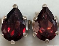 Close-up of the front view of the garnet earrings showing the deep red faceted teardrop stones set in silver prongs.