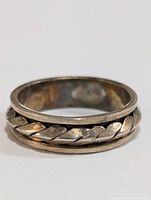 Silver ring showing braided middle design and smooth edges interior and exterior, size 8.