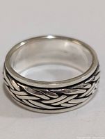 Front view of silver ring showing braided band design and polished edges.