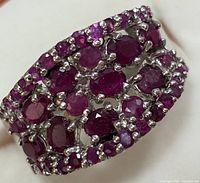 Close-up photo showing the detailed ruby settings and silver band structure.