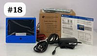 Blue frame 7-inch public view monitor with integrated camera, cables, power adapter, and user manual. Lot includes original packaging and printed instructions.