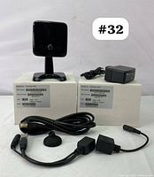 Two iCamera-1000 IP security cameras displayed with original boxes, power adapters, Ethernet cable, and connectors arranged in front.