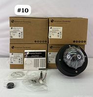 One black dome-style camera with tinted dome, sealed, alongside installation manual and mounting hardware, with remaining three cameras boxed.