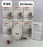Set of 23 DSC PowerG wireless PIR motion detector boxes with one detector, battery, red screws, and instruction manual displayed.