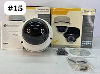 Photo of one Illustra 610 HD IP Outdoor Mini-Dome Security Camera with its box, manual, mounting kit, and driver CD showing front camera dome and packaging.