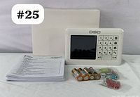 Photo of DSC WK250 keypad, user manual, four AA batteries, small keys, mounting screws, wall anchors and blank card on gray surface.