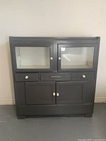 Front view of full cabinet showing glass upper doors, drawers, lower doors, and white insulator knobs as handles.