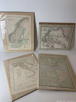 Four antique maps laid flat on a white surface, each in a brown cardboard backing and clear plastic sleeves.