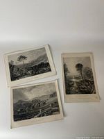 Three antique English origin prints laid out on a flat surface, showing rural and castle scenes in monochrome.