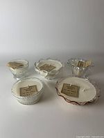 Front view of 5 handmade vanilla bean soy wax candles each in unique vintage glass vessels, showing variation in shapes and glass details.