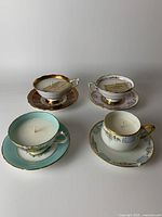Overview of 4 handmade soy wax candles in vintage teacups placed on matching saucers