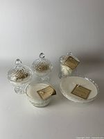 Photo of five handmade unscented soy wax candles, three with lids and two open, sitting on a white surface grouped together.