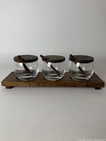Full view of the glass jars with teak wood lids and spoons arranged on the teak tray.