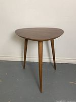 Front view of the solid wood triangular side table showing the smooth top and three tapered legs.