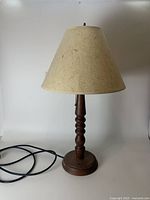 Full view of the MidCentury teak table lamp showing carved wood base and beige fiber-textured lampshade with pull chain.