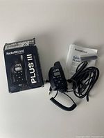 Three PocketWizard Plus III transceivers shown with original box, one unit connected to coiled sync cable, and quick start guide booklet.