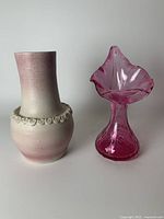 Photo showing the two pink vases side by side on a plain background to highlight their shapes and decorative elements.