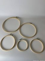 Overview of all five wood embroidery hoops with metal screws laid flat on white surface, showing size variety.