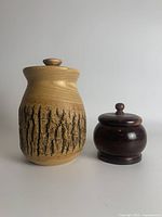 Photo showing both wooden canisters together, highlighting the taller bark-covered canister and the smaller polished walnut canister side by side.