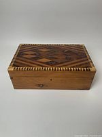 Top view of handcrafted wooden jewelry box showing intricate geometric wood inlay design and zigzag border