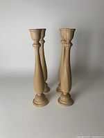 Photo showing four wooden candlesticks standing upright, displaying their height and shape.