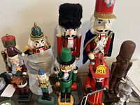 Full display of various wooden nutcracker figures in an assortment of colors and sizes, including a taller black-furred hat soldier and a red-hatted soldier holding a 'No. 1' sign.