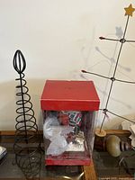 Photo of boxed snowboarder nutcracker alongside two metal Christmas tree sculptures on a wooden table.