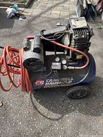 Full view of compressor showing tank, motor, hoses and wheels