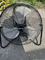 Front view of Mastercraft floor fan showing black wire mesh guard and three metal blades