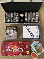 Poker chip set in metal case with dealer and blind buttons, double 15 domino game, Sequence game, Scrabble board game, Uno cards, and Boxer and Briefs board game visible.