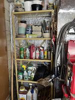 Five-tier wooden shelving unit with a variety of gardening supplies including pots, sprays, and a gardening shovel.