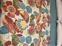 Close-up of colorful floral fabric showing detailed flower and leaf motifs in multiple colors and stitching texture.