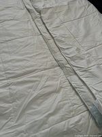 Close-up of white king size wool duvet showing quilted cotton cover with smooth fabric surface and stitched edges.