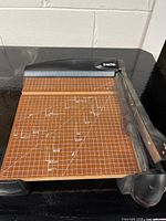 Full view of X-Acto paper guillotine cutter showing brown grid cutting surface with angle and measurement guides.