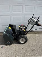 Side view of entire snow blower showing housing, engine, wheels and handle