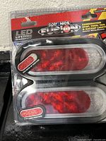 Photo showing a sealed Optronics Fusion LED trailer light set with oval-shaped lenses featuring stop, turn, tail, and backup functions.