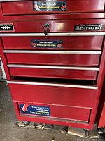Front view of lower rolling cabinet showing five drawers, Mastercraft logo, drawer liners sticker and caster wheels.