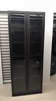 Front view of tall black Ikea Billy XL bookshelf with glass doors closed.