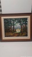 Framed oil painting showing entire forest scene with path and distant lake, including frame details