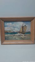 Frontal view of the oil painting showing boats, water, sky, birds, cliffs, and wooden frame.