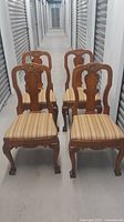 Set of 4 vintage wooden dining chairs with striped removable seat cushions, showing the front view in a hallway.