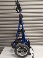 Side view of folded blue Sun Mountain golf push cart showing metal frame and large wheels