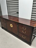 Full side view of wooden dresser showing drawers and cabinet doors. Glossy finish and slight reflection visible on top surface along with small white stain.