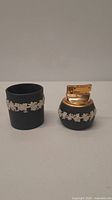 Photo showing both the lighter and ashtray side by side, highlighting the black glass with white floral relief decoration and gold-tone lighter top