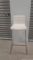 Side view of white kitchen bar stool showing contoured hard plastic seat and curved chrome metal legs.