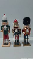 Front view of all three wooden nutcrackers showing their differences in color, size, and costume.
