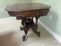 Front-left angled view showing the mahogany base with intricate carvings and marble top.